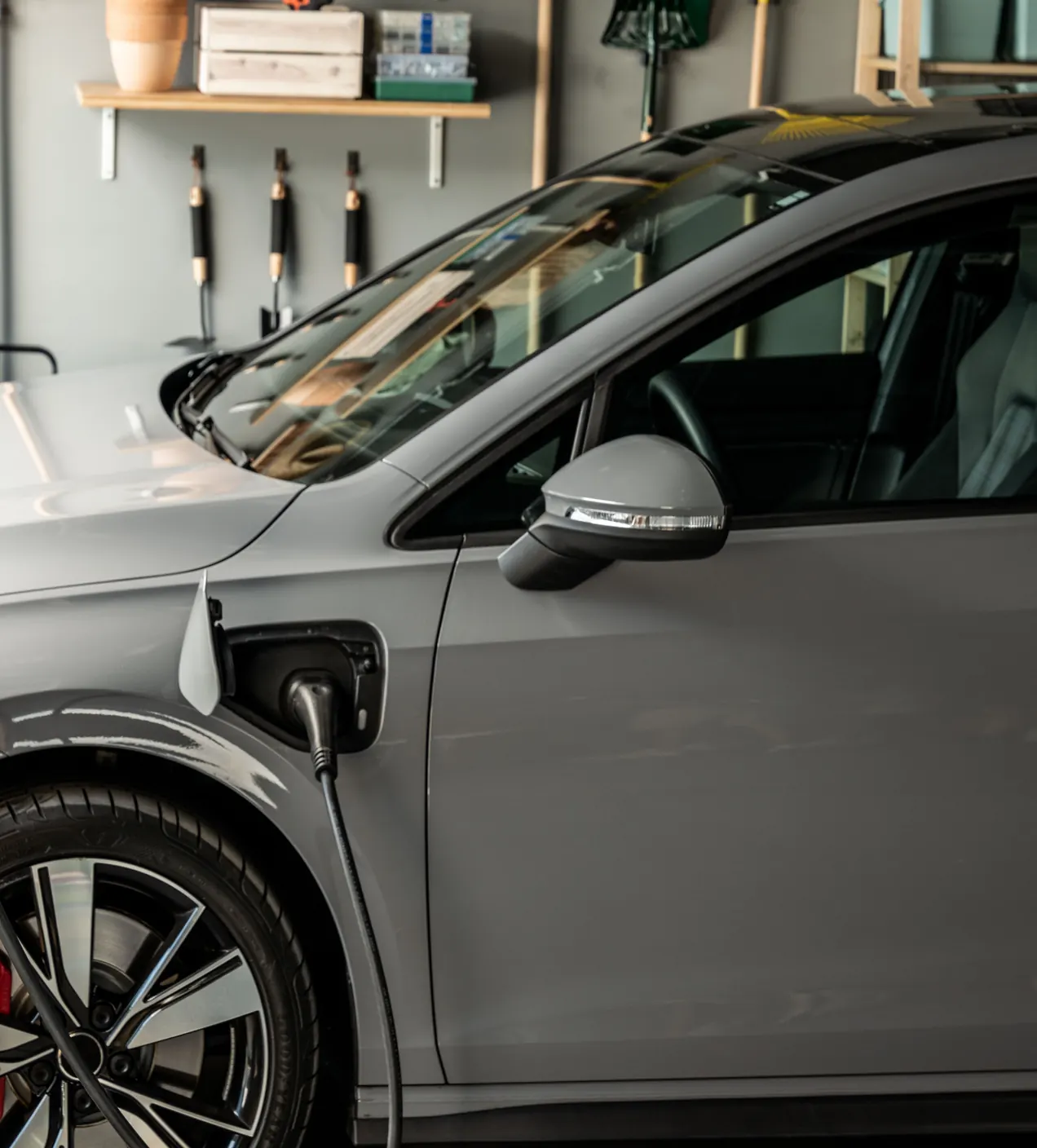 Garázsban töltődő ezüst elektromos autó
