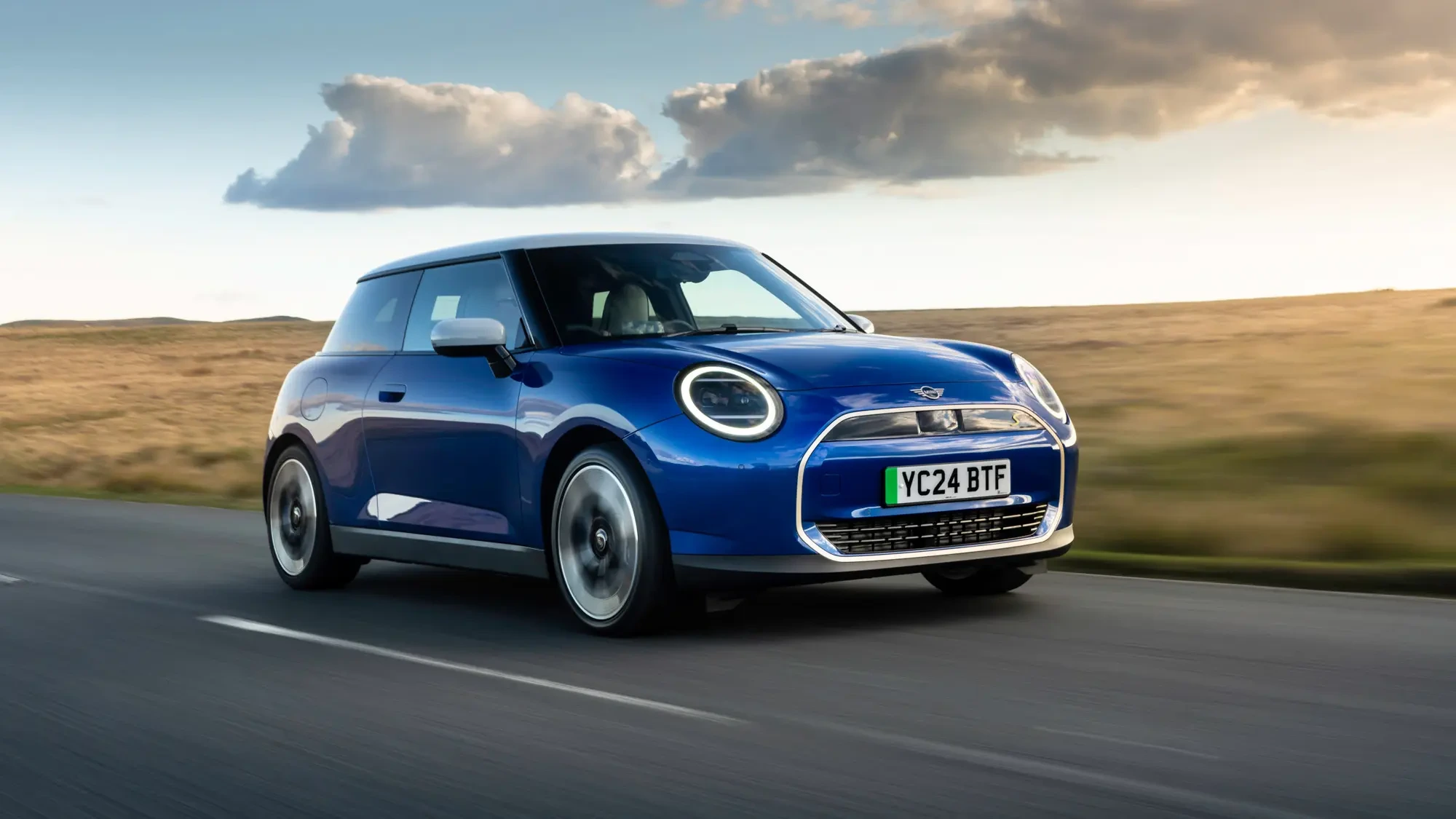 Kék elektromos kisautó menet közben, modern elektromos autó kis méretben, hatékony motor és akkumulátor, városi és elővárosi közlekedésre alkalmas elektromos jármű akár hosszú töltési idővel is.