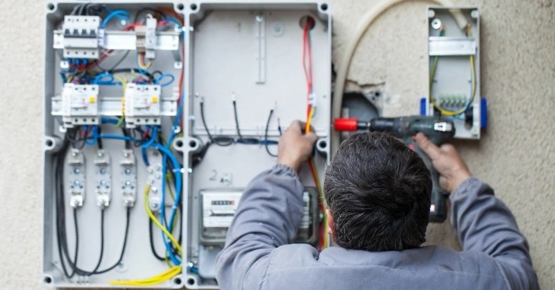 Villanyszerelő a mérőórát és a kismegszakítókat szereli az elektromos autó töltő teljesítménybővítéséhez